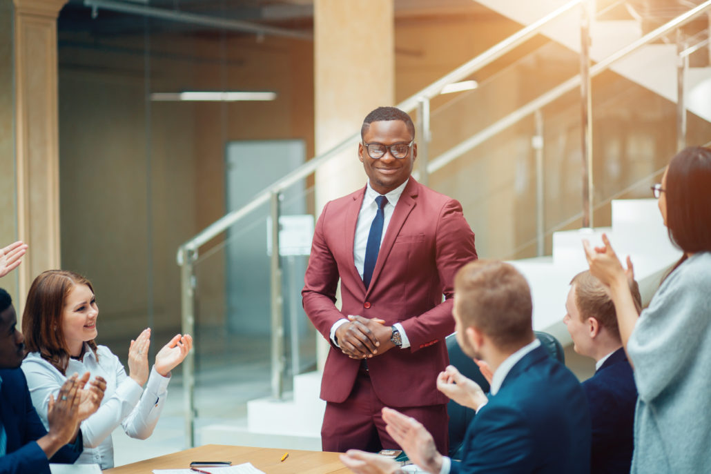 smiling black male boss talking to business team