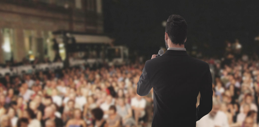 Uomo canta parla sul palco folla